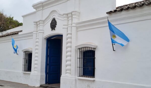 Imagen contextual de la Casa Histórica de la Independencia en San Miguel de Tucumán, con banderas argentinas en su fachada.
