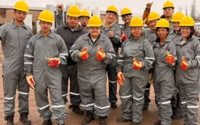 Jóvenes participantes de una capacitación para ingresar a la industria petrolera posan con cascos y ropa de seguridad industrial.