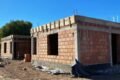 Obra en construcción de viviendas del programa Tenemos Futuro, con paredes de ladrillo y estructuras de hormigón.