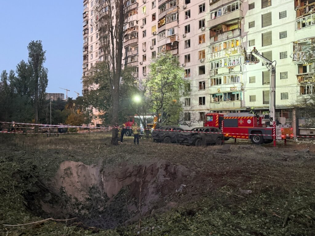 Personal de emergencia trabaja junto a un cráter y un edificio residencial dañado tras los ataques en Kiev.