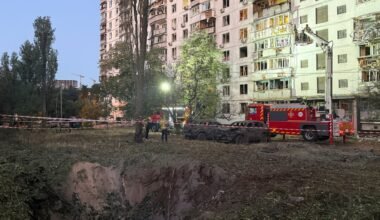 Personal de emergencia trabaja junto a un cráter y un edificio residencial dañado tras los ataques en Kiev.