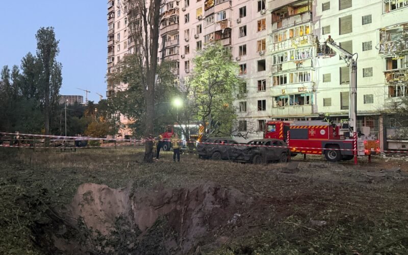 Personal de emergencia trabaja junto a un cráter y un edificio residencial dañado tras los ataques en Kiev.