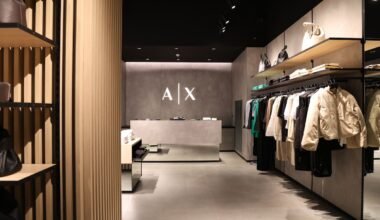 Interior del nuevo local de Armani Exchange, con prendas y accesorios exhibidos y el logotipo A|X en la pared.