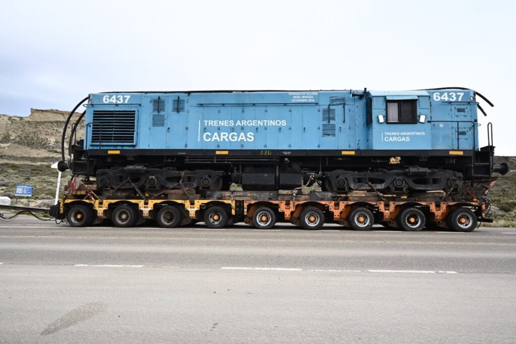 La locomotora 6437 de Trenes Argentinos Cargas es trasladada sobre un carretón por una ruta patagónica.