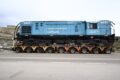 La locomotora 6437 de Trenes Argentinos Cargas es trasladada sobre un carretón por una ruta patagónica.