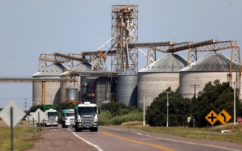 Imagen contextual de una planta de acopio o procesamiento de granos con camiones.
