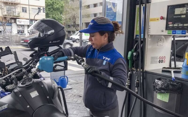 Imagen contextual de una trabajadora de YPF cargando combustible en una estación de servicio.