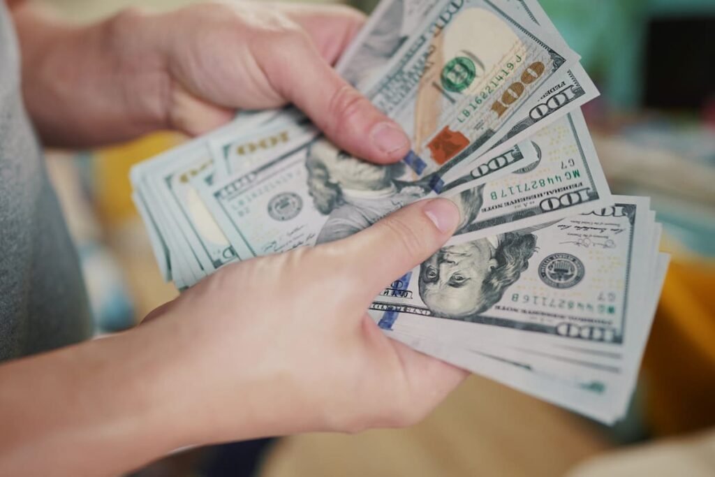 Imagen contextual de una persona contando billetes de dólares estadounidenses.