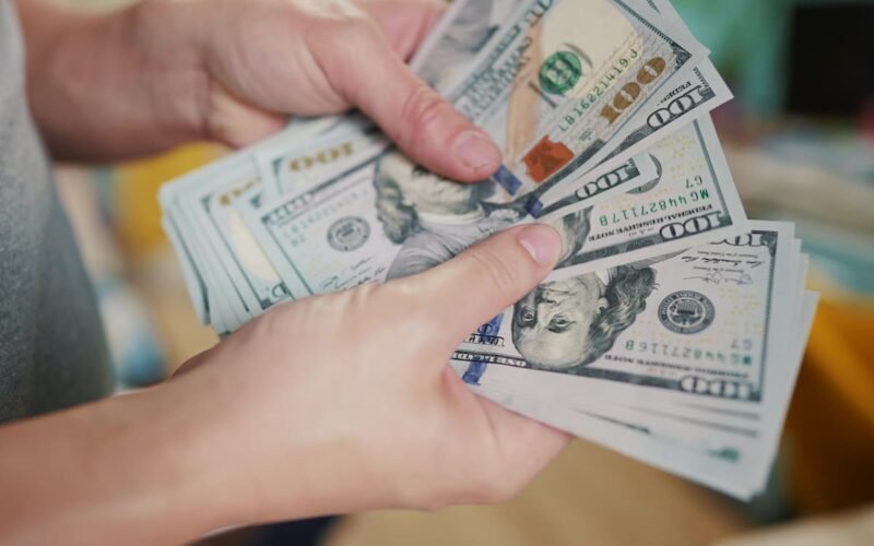 Imagen contextual de una persona contando billetes de dólares estadounidenses.