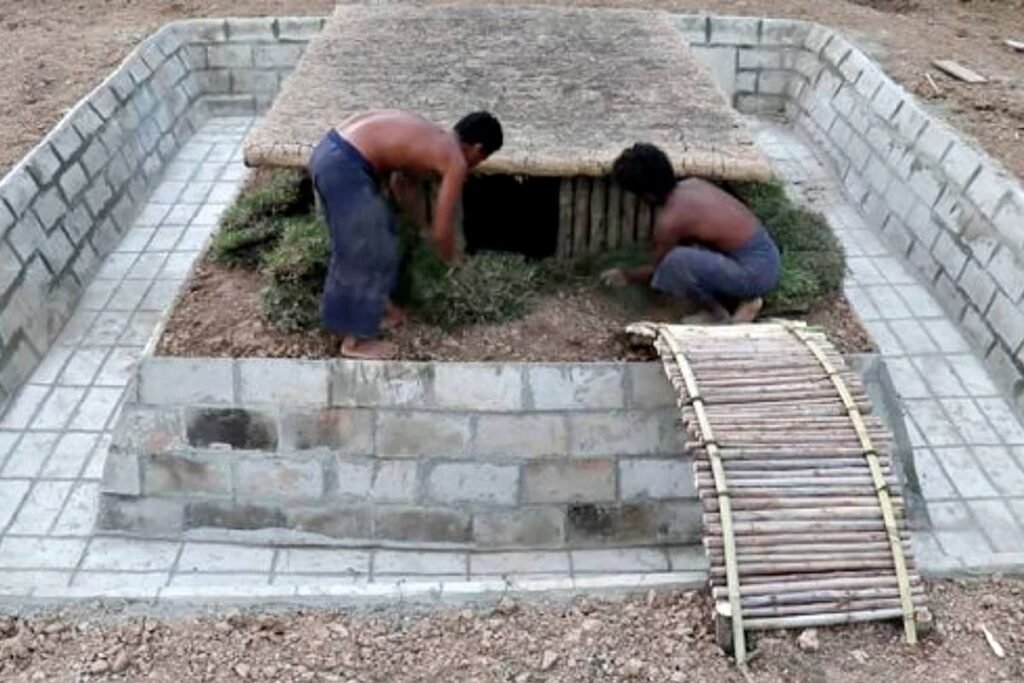 Dos personas trabajan en una vivienda semienterrada rodeada por una pileta en construcción.