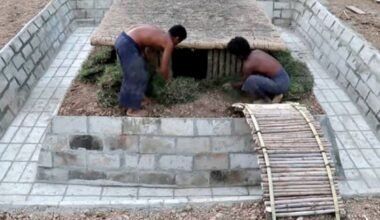 Dos personas trabajan en una vivienda semienterrada rodeada por una pileta en construcción.