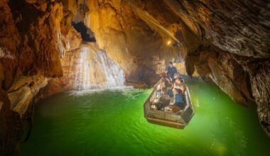 Visitantes recorren en barca la Rivière Souterraine de Labouïche, entre formaciones rocosas subterráneas.