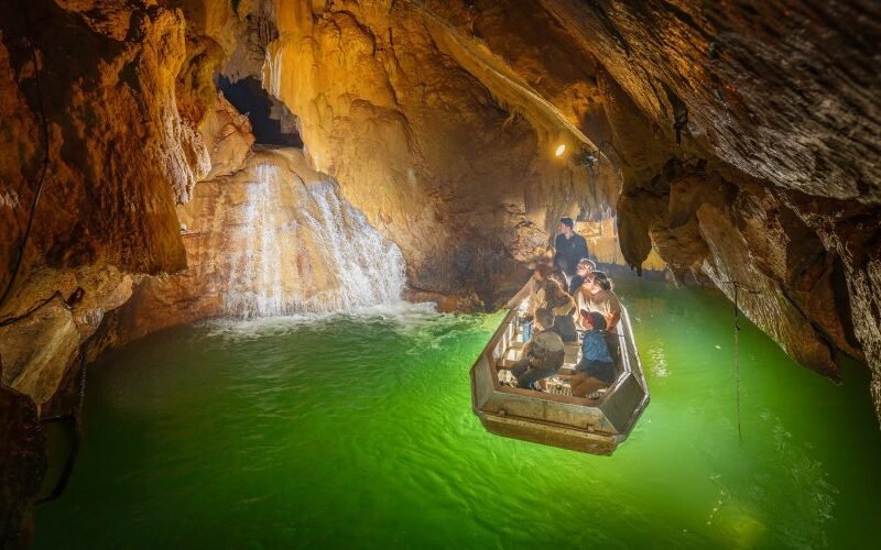 Visitantes recorren en barca la Rivière Souterraine de Labouïche, entre formaciones rocosas subterráneas.