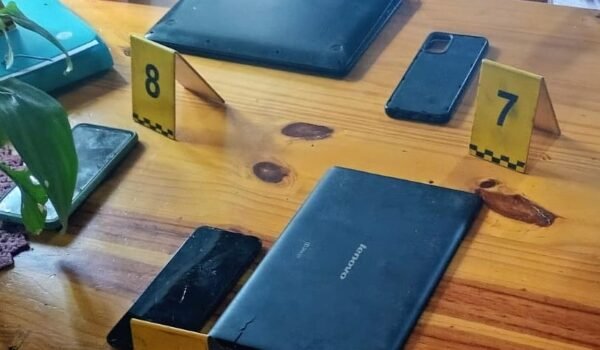 Celulares y otros dispositivos secuestrados durante los allanamientos, junto a marcadores de evidencia.