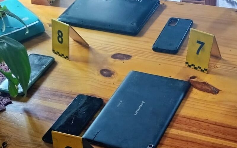 Celulares y otros dispositivos secuestrados durante los allanamientos, junto a marcadores de evidencia.