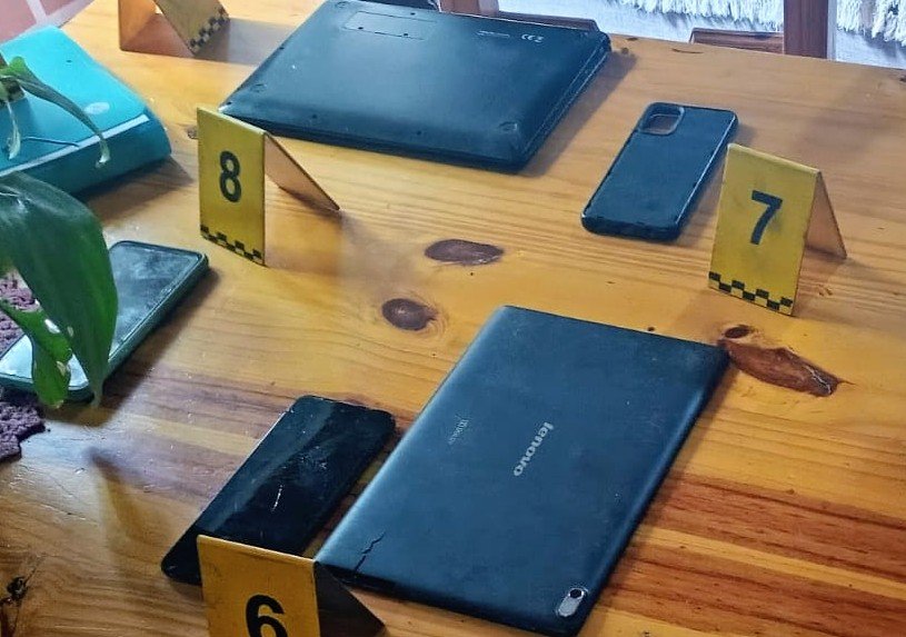 Celulares y otros dispositivos secuestrados durante los allanamientos, junto a marcadores de evidencia.