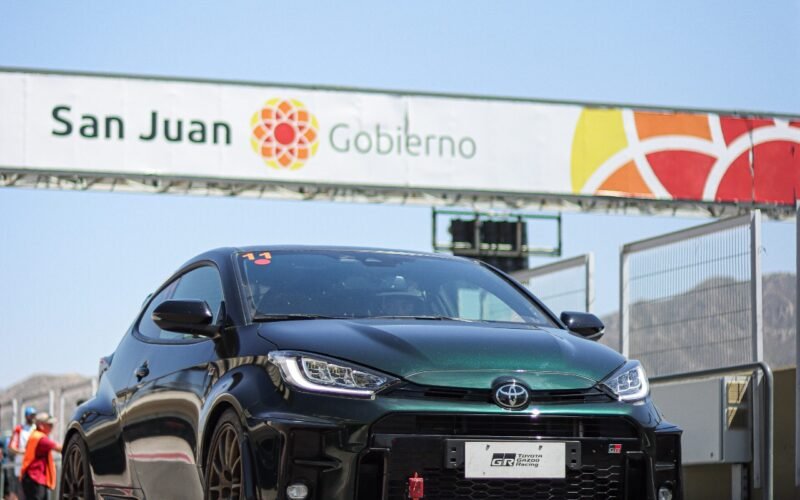 Imagen contextual de un auto deportivo junto a un acceso con el cartel de San Juan Gobierno.