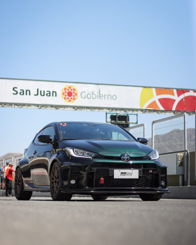 Imagen contextual de un auto deportivo junto a un acceso con el cartel de San Juan Gobierno.