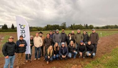 Productores posan en un campo de ensayos de cebada durante la visita.