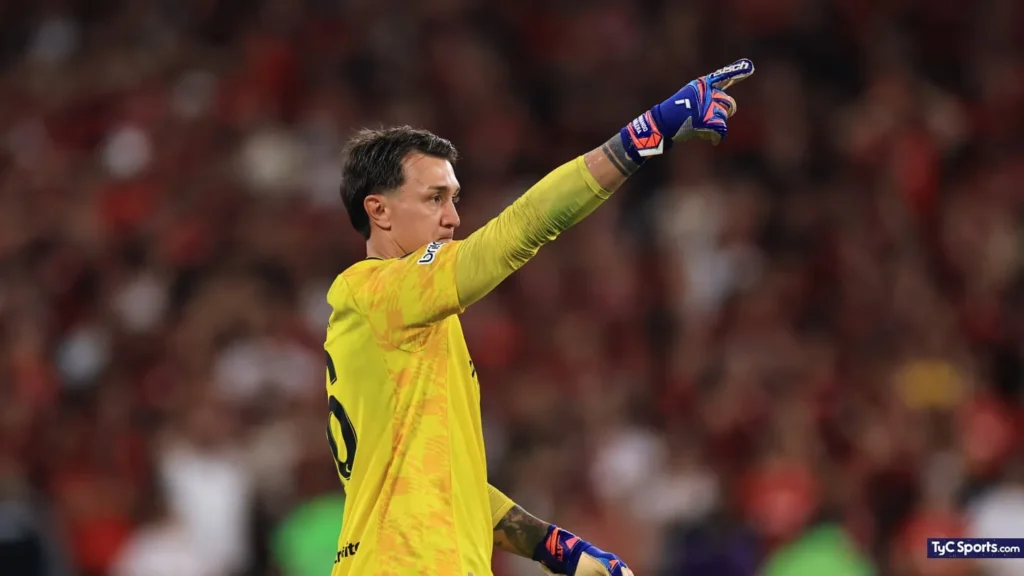 Fernando Muslera, con la camiseta amarilla de arquero, señala hacia el campo durante el partido.