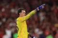 Fernando Muslera, con la camiseta amarilla de arquero, señala hacia el campo durante el partido.