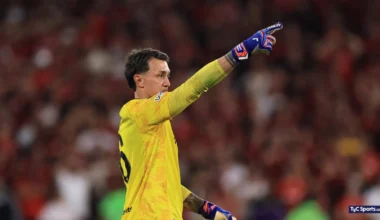 Fernando Muslera, con la camiseta amarilla de arquero, señala hacia el campo durante el partido.