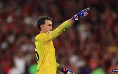 Fernando Muslera, con la camiseta amarilla de arquero, señala hacia el campo durante el partido.